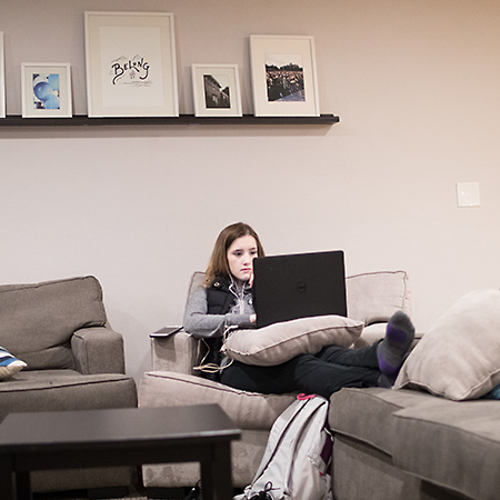 A student sitting on a sofa with her laptop in the FoxHole, a commuter lounge