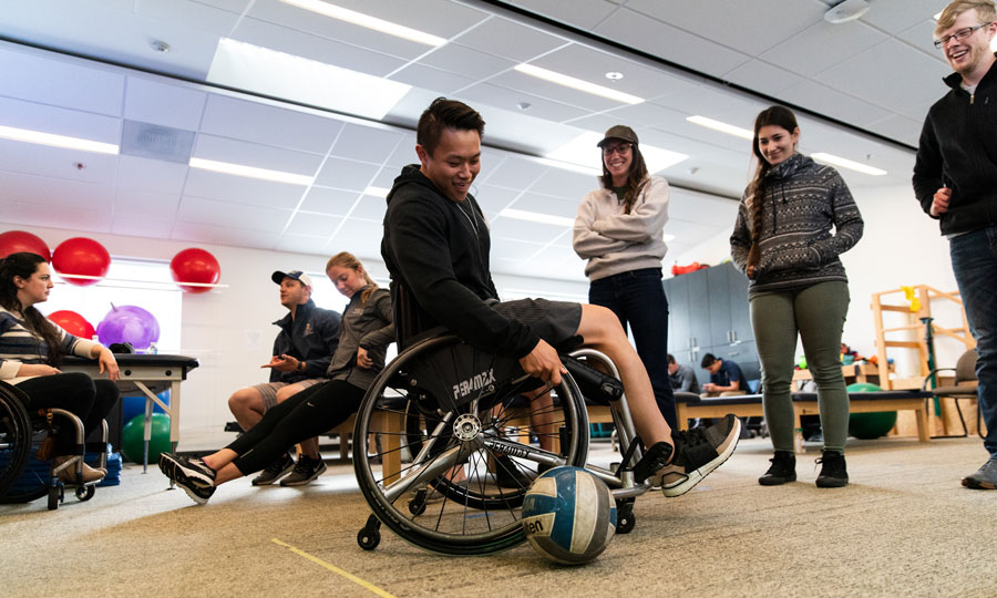Group of students take turns in a wheelchair