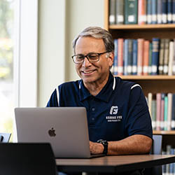 Smiling man sits at computer