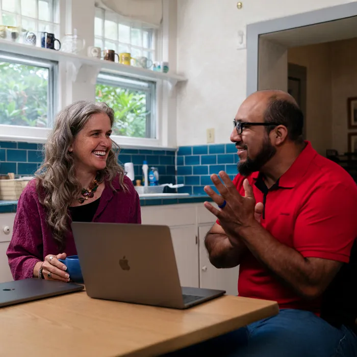 An adult student sits at a desk with a peer while they work on an assignment