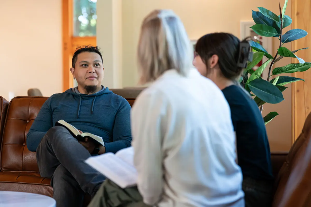 Dominic Abaria sits with two women in a church