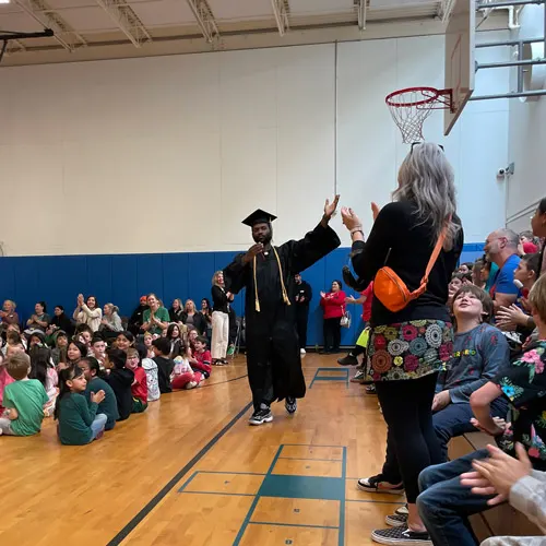 Jason Murray waves to kids in graduation regalia
