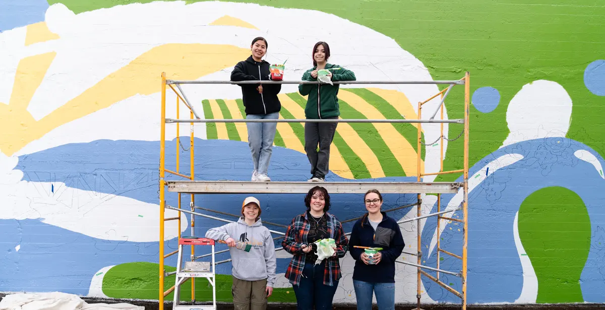 Students stand in front of their mural in process