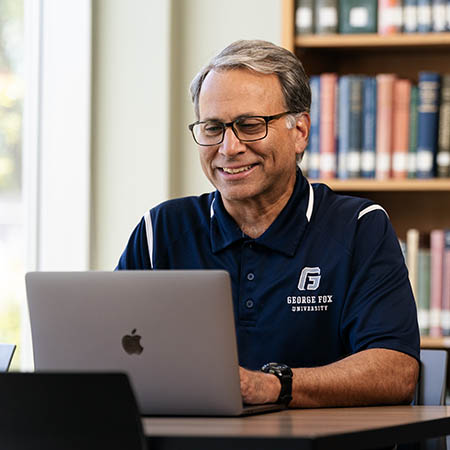 smiling man sits at computer