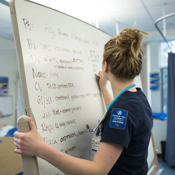 Nursing student writes on whiteboard