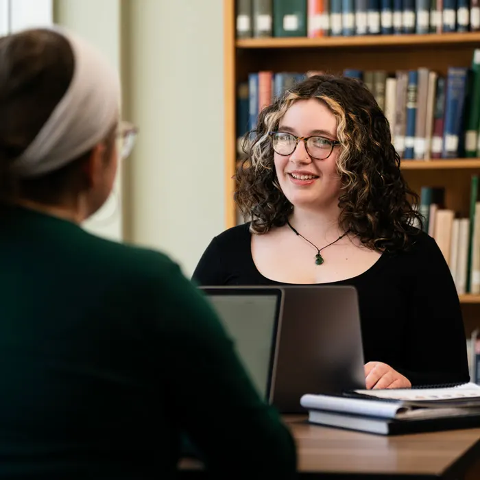 Student talks with another in the library