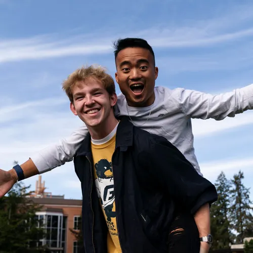 Two students piggyback for a photo on the quad on campus during Scholarship Summit