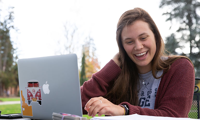 Photo of a student on a laptop outside