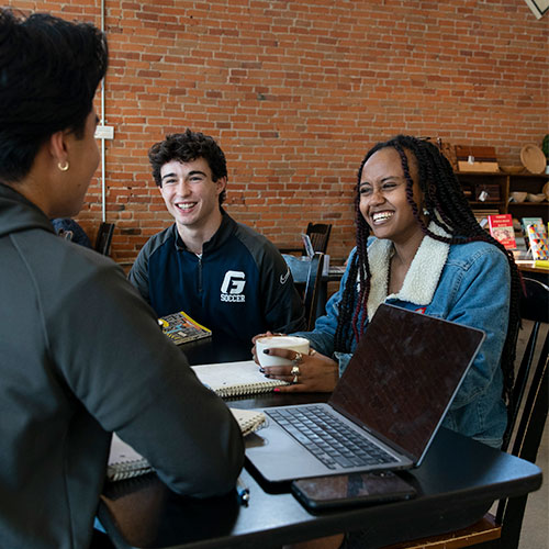 Three students having a conversation in a coffee shop