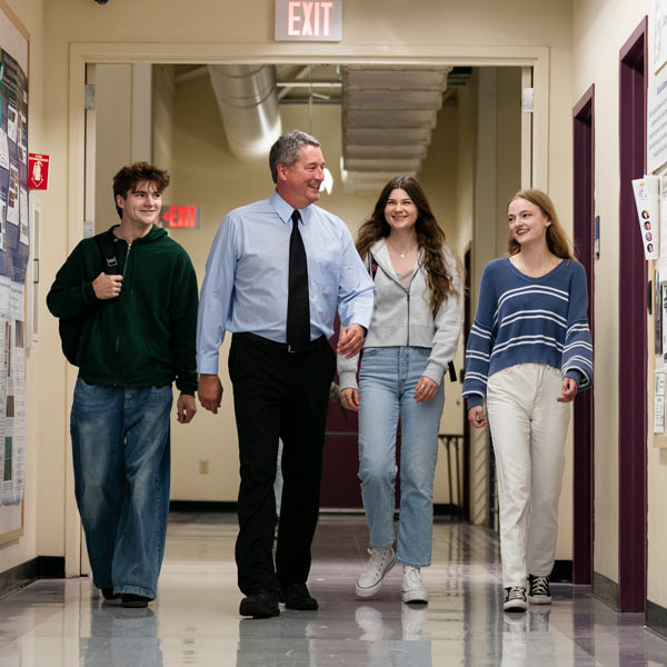 School administrator walks with students through the hall