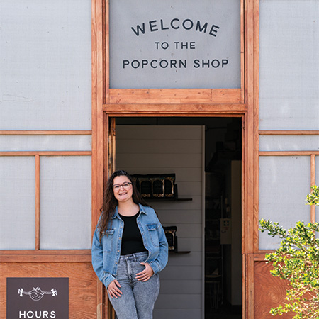 Hannah Jodoin standing in front of her gourmet popcorn shop